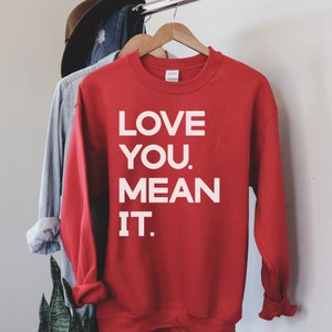 May include: Red sweatshirt with white text that reads "LOVE YOU. MEAN IT."