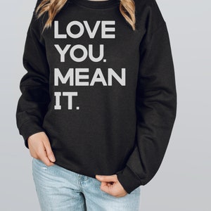 May include: Black sweatshirt with white text that reads "LOVE YOU. MEAN IT."