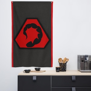 May include: A rectangular wall flag with a black background and a red border. The flag features a red hexagon with a black scorpion design in the center. The flag is hanging on a white wall.