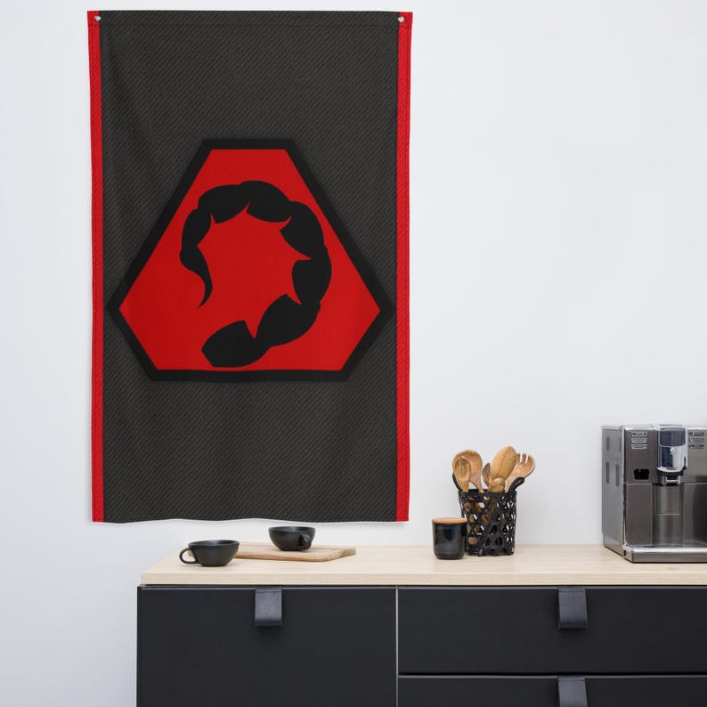 May include: A rectangular wall flag with a black background and a red border. The flag features a red hexagon with a black scorpion design in the center. The flag is hanging on a white wall.