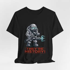 May include: Black t-shirt featuring a cartoon soldier in a gas mask and armor holding a futuristic weapon with a blue energy blast. The text "THEY'RE HISTORY!" is printed in red below the illustration.