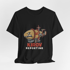 May include: Black t-shirt featuring a cartoon zeppelin with a menacing face, red accents, and the text "KIROV REPORTING" in red and white. The zeppelin design is brown and tan with a red star and propeller.