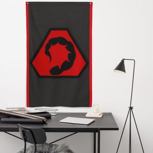 May include: A black wall flag with a red border and a central design. The design features a black scorpion silhouette within a red hexagon, set against a textured black background. The flag is hanging on a white wall.