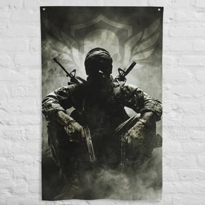 Pode incluir: Uma bandeira de parede com um soldado em uniforme de camuflagem, sentado com uma pistola e dois rifles. A imagem é em tons de cinza e preto, com um efeito esfumaçado e um desenho de brasão no fundo.