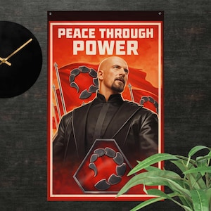Op de afbeelding: Een wandkleed met de tekst "PEACE THROUGH POWER" in witte letters op een rode achtergrond. De afbeelding toont een man in een zwart uniform, met een kale kop en een sik. Een zwart schorpioen-embleem is zichtbaar.
