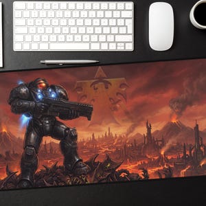 Pode incluir: Tapete de rato retangular para jogos com uma cena de ficção científica de um soldado futurista segurando uma arma, ambientada em uma paisagem vulcânica e ardente. O tapete tem uma borda preta e é cercado por um teclado, mouse e xícara de café.