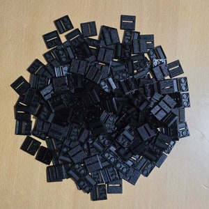 May include: A large pile of black plastic Lego bricks. The bricks are all the same size and shape, and they are arranged in a random pattern.