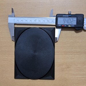 Op de afbeelding: Een zwart rond object van plastic met een diameter van 23,88 cm, gemeten met een digitale schuifmaat.