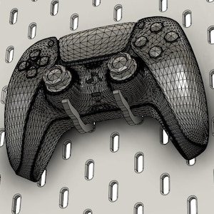 Peut inclure: Une manette de jeu noire en fil de fer est montée sur un panneau perforé blanc. La manette a un design symétrique avec des boutons, des joysticks et des gâchettes. Le panneau perforé présente un motif répétitif de trous ovales.