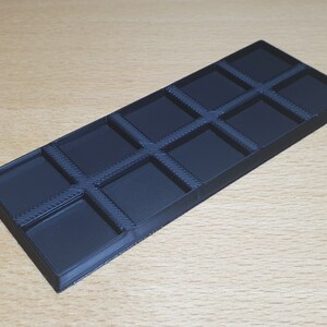 May include: A black plastic tray with 10 square compartments. The tray is designed to hold small items, such as jewelry or craft supplies.