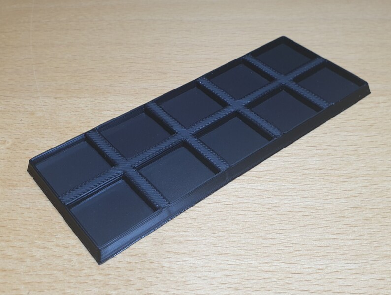 May include: A black plastic tray with 10 square compartments. The tray is designed to hold small items, such as jewelry or craft supplies.