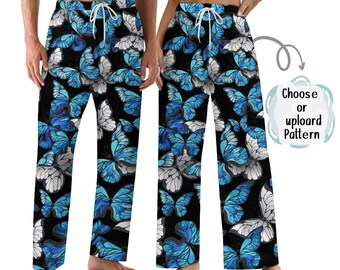Puede incluir: Pantalones de pijama negros con un patrón repetido de mariposas azules y blancas. Los pantalones tienen cintura con cordón. Las mariposas tienen patrones de alas detallados sobre un fondo negro. Se muestra en dos personas.