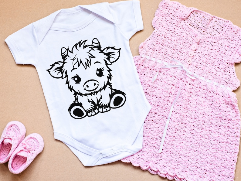 May include: A white baby onesie with a black and white illustration of a cartoon cow. The onesie has short sleeves and a snap closure at the bottom.