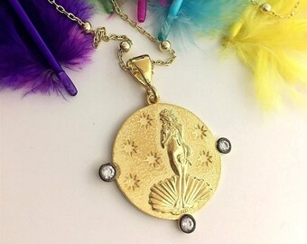 May include: A gold necklace with a round pendant featuring a detailed image of the Birth of Venus. The pendant is accented with three small clear stones.