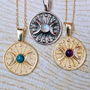 May include: Three celestial-themed necklaces. Two are gold-toned, featuring a central stone and crescent moon design. The third is silver-toned with a similar design and a central stone. All have delicate chains.