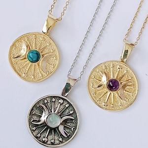 May include: Three celestial-themed pendant necklaces. Two are gold-toned, one with a turquoise stone and the other with an amethyst. The third necklace is silver-toned with a pearlescent stone. Each pendant features a sun, moon, and star design.