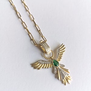 Pode incluir: Um colar de corrente de ouro com um pingente que apresenta um anjo estilizado com asas, uma gema verde e diamantes pav&eacute;.