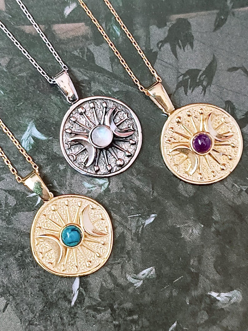 May include: Three celestial-themed pendant necklaces. One silver-toned necklace features a round pendant with a moonstone center. Two gold-toned necklaces have pendants with turquoise and amethyst centers. Each necklace has a delicate chain.