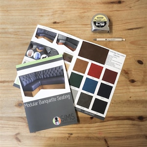 May include: A brochure for modular banquette seating with a variety of fabric swatches in different colours. The brochure features the text "Modular Banquette Seating" and the company logo "SIMS Contract Furniture Ltd.". The fabric swatches are labelled with names like "Deep Tan", "Red", "Navy", "Charcoal", and "Black".