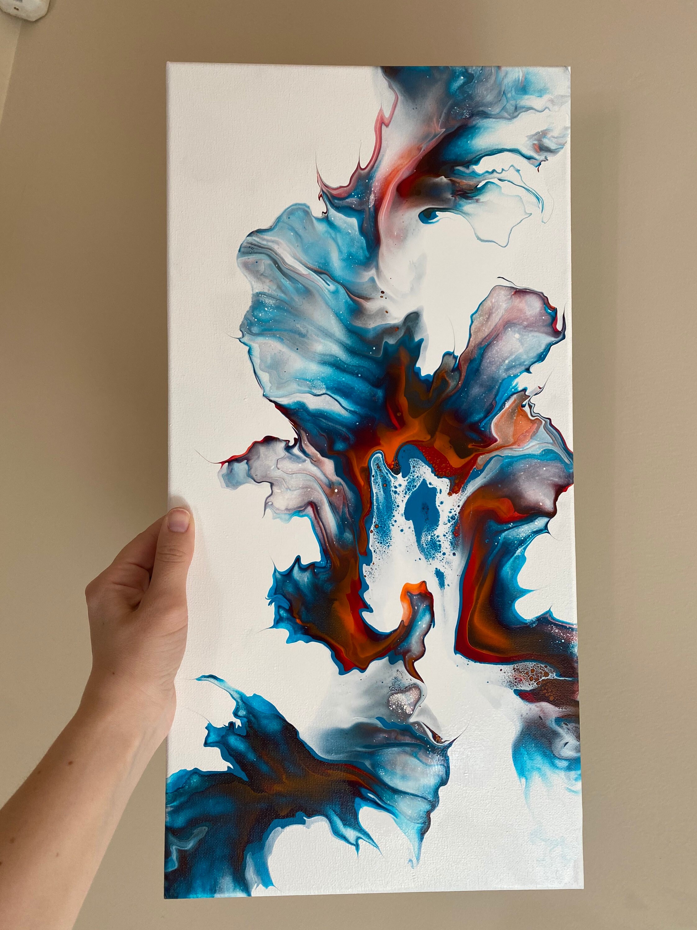 Red, blue, orange and gold abstract fluid acrylic Dutch pour painting on a white background. 10” x 20”