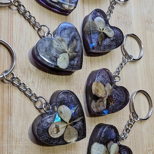 Purple Heart Hydrangea Keychains - real dried flowers in clear resin above a dark purple background with swirls of silver