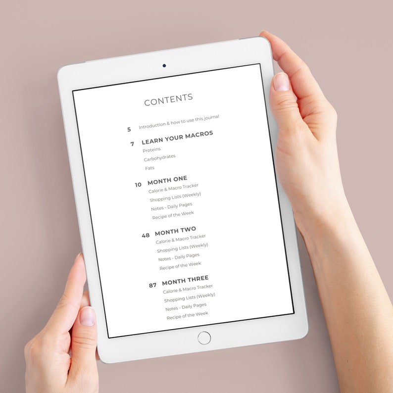 May include: A white tablet displaying a digital contents page for a journal. The text lists sections including Introduction, Learn Your Macros, Month One, Month Two, and Month Three, with corresponding page numbers and sub-topics like Calorie & Macro Tracker.