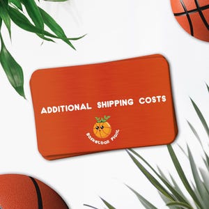 Könnte beinhalten: Eine orangefarbene Karte mit dem Text "ADDITIONAL SHIPPING COSTS" und einem Cartoon-Basketball-Pflanzen-Logo. Zwei Basketbälle und grüne Blätter befinden sich im Hintergrund.