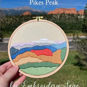 May include: Embroidered hoop art depicting a colorful landscape of mountains and sky, with the text "Garden of the Gods & Pikes Peak" and "by Embroidery Sage" below the image.