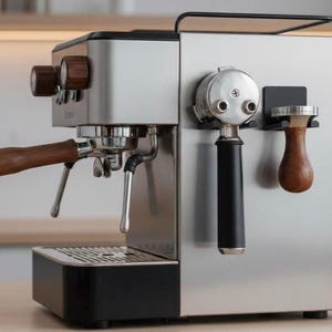 Könnte beinhalten: Espressomaschine aus Edelstahl mit Holzakzenten. Mit Siebträger, Tamper und Dampflanze. Die Maschine hat einen schwarzen Sockel und eine Metalloberseite mit Holzknöpfen. Ein elegantes Gerät für Kaffeeliebhaber.
