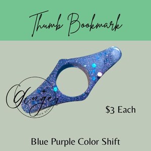 May include: A blue and purple color shift thumb bookmark with glitter. The bookmark has a circular opening for the thumb and a flat, angled top. The text "Thumb Bookmark" is at the top, and "Blue Purple Color Shift" is at the bottom.