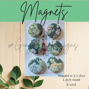 May include: Six round magnets with floral and succulent designs. The magnets are 1 inch in diameter and feature a variety of green, pink, and white floral patterns on a dark background. The word "Magnets" is written in cursive.