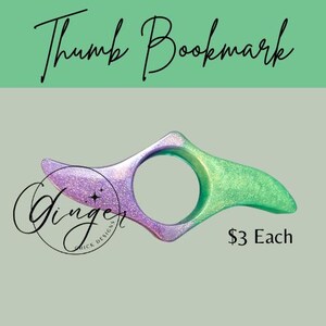 May include: A thumb bookmark with a glittery purple and green design. The bookmark has a circular opening for the thumb and is labeled "Thumb Bookmark" in script. The Ginger Chick Designs logo is also visible.