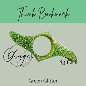 May include: Green glitter thumb bookmark with a circular opening. The bookmark has a curved design and is labeled "Thumb Bookmark" in cursive. The text "Ginger Chick Designs" is also visible.