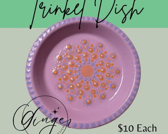 May include: A round, lavender trinket dish with a mandala design in orange and light blue. The dish has a dotted border and the text "Trinket Dish" in cursive. The Ginger Chick Designs logo is also visible.