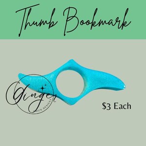 May include: A turquoise thumb bookmark with glitter, featuring a circular opening for the thumb and a curved design. The text "Thumb Bookmark" is at the top, and a logo and the text "$3 Each" are also visible.