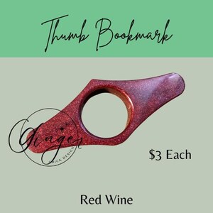 May include: A red wine-colored thumb bookmark with glitter, featuring a circular opening for the thumb. The text "Thumb Bookmark" is at the top, with "Ginger Quick Design" and "Red Wine" at the bottom.