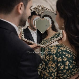May include: A decorative mirror with a heart-shaped center, framed with pearls and ornate gold accents. The mirror reflects a couple, with the text "Best Creativity Finds" visible.