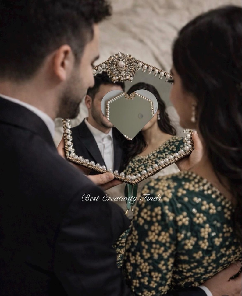 May include: A decorative mirror with a heart-shaped cutout, framed with pearls and gold accents. The mirror reflects a couple, with the text "Best Creativity Finds" visible.