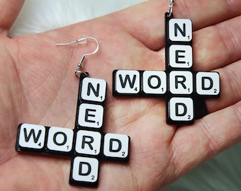May include: A pair of black and white Scrabble tile earrings spelling out "WORD" and "NERD".