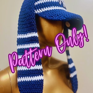 May include: A handmade blue and white crochet hat with long ear flaps. The hat features a baseball cap style visor and a white logo. The ear flaps have white stripes. The text "Pattern Only!" is visible.