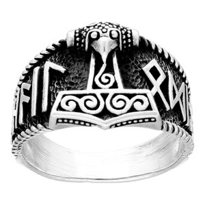 Può includere: Un anello d'argento con un designo dettagliato del martello di Thor, Mjolnir, con una testa d'aquila in cima. L'anello è decorato con dettagli intricati e le rune "Futhark" sono incise sulla fascia.