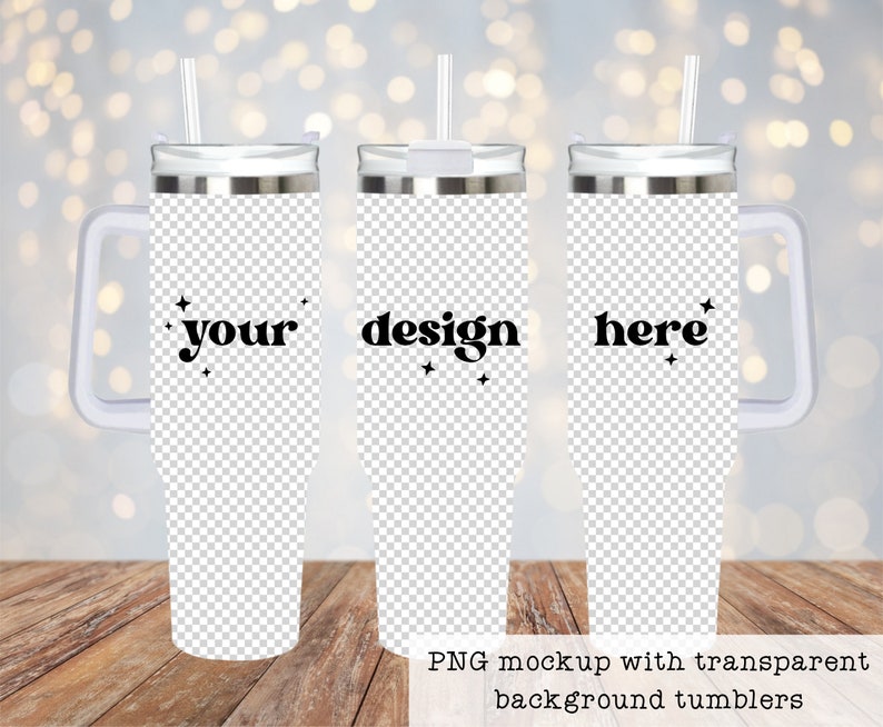 May include: Three stainless steel tumblers with a white handle and a straw. The tumblers are on a wooden surface. The tumblers have a transparent background and the text "your", "design", and "here" is printed on them.