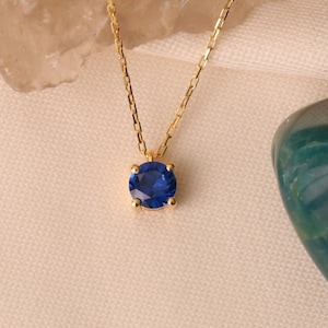 May include: A gold chain necklace with a blue gemstone pendant.