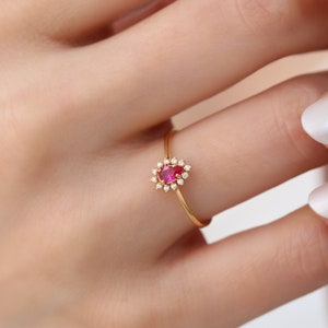 Op de afbeelding: Een gouden ring met een roze ovale edelsteen omringd door kleinere witte edelstenen.