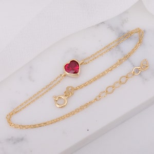 Peut inclure: Un bracelet en chaîne dorée avec un pendentif en forme de cœur rouge. Le bracelet est muni d'un fermoir à ressort et d'une chaîne d'extension.