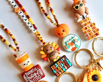 May include: Four beaded lanyards featuring autumn-themed charms including a pumpkin, a turkey, a coffee cup, and a cooked turkey wearing sunglasses. Each lanyard includes letter beads spelling phrases like GIVE THANKS and THANKFUL GRATEFUL BLESSED.