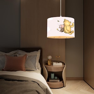 Könnte beinhalten: Eine runde Deckenleuchte im Winnie-the-Pooh-Design in Weiß und Rosa. Der Schirm zeigt ein Cartoon-Bild von Winnie Puuh und Ferkel, die durch die Luft fliegen.