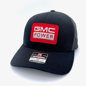 May include: Black trucker hat with a red and white patch that says "GMC POWER". The hat is adjustable and has a black mesh back.