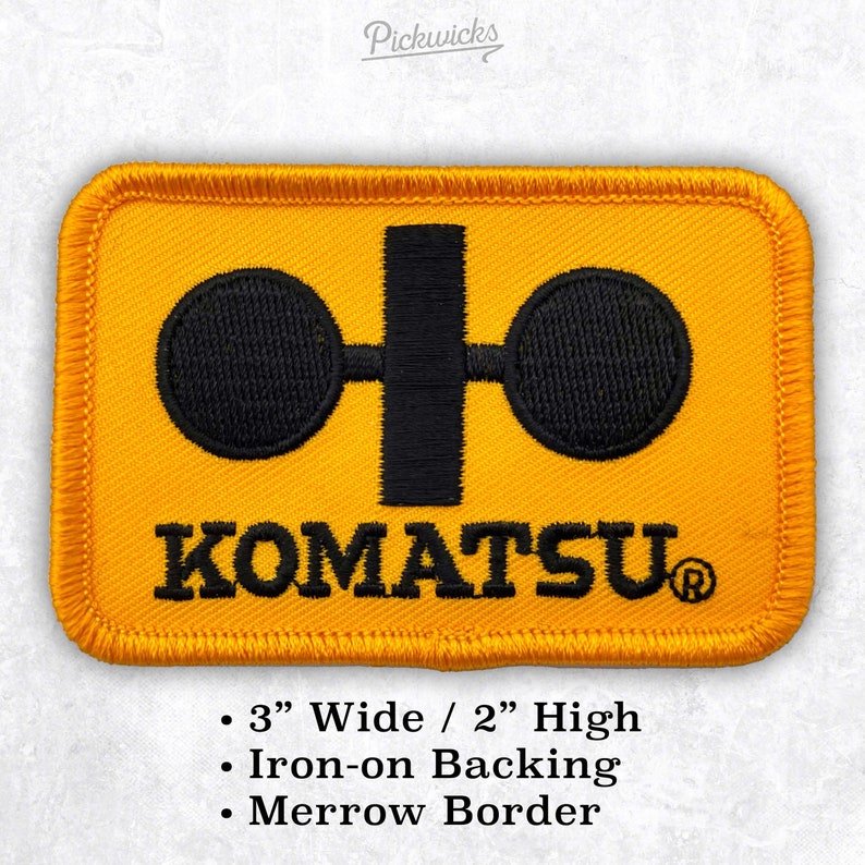 Pu&ograve; includere: Toppa da stirare gialla con logo Komatsu nero. Il logo presenta due cerchi collegati da una barra verticale. Il testo "KOMATSU&reg;" &egrave; sotto il logo. La toppa &egrave; larga 7,6 cm e alta 5,1 cm.