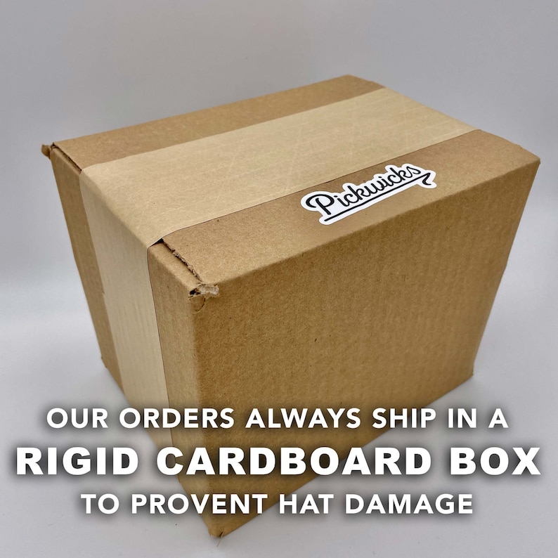 May include: A brown cardboard box with a white label that says "Pickwick's" with an arrow. The box is taped shut. The text below the box reads "Our orders always ship in a rigid cardboard box to prevent hat damage."